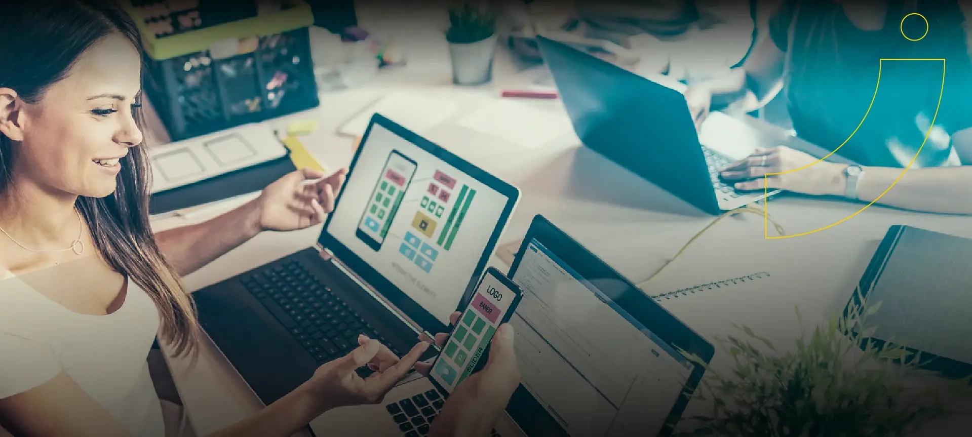Mujer con dos laptops observando un celular